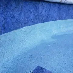 Waterline tile and speckled pebble pool finish seen close up under clear water
